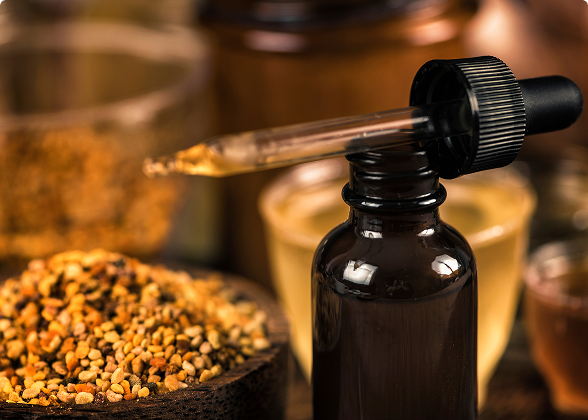 Frasco de extrato de própolis com conta-gotas ao lado de uma tigela com pólen.