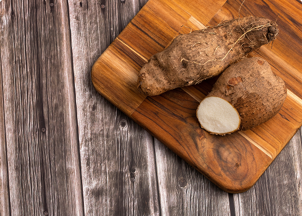 Dois inhames sobre uma tábua de madeira, sendo um deles cortado ao meio.